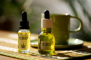 Two CBD Vape oil dropper bottles on a table with a blurred background