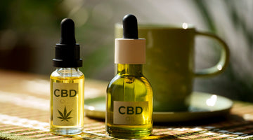 Two CBD Vape oil dropper bottles on a table with a blurred background