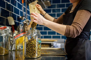 CBD flower being poured from a baking sheet in to a jar