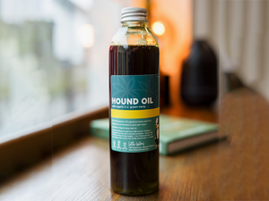 Bottle of 'Hound Oil' CBD for Pets on a wooden surface with a blurred background