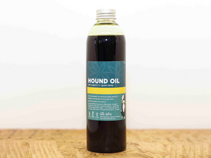 Bottle of CBD for Pets 'Hound Oil' on a wooden surface with a white background