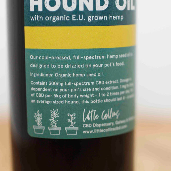 Bottle label for a CBD oil for pets, dogs and cats, with organic E.U. grown hemp, featuring text about CBD usage on a wooden surface.
